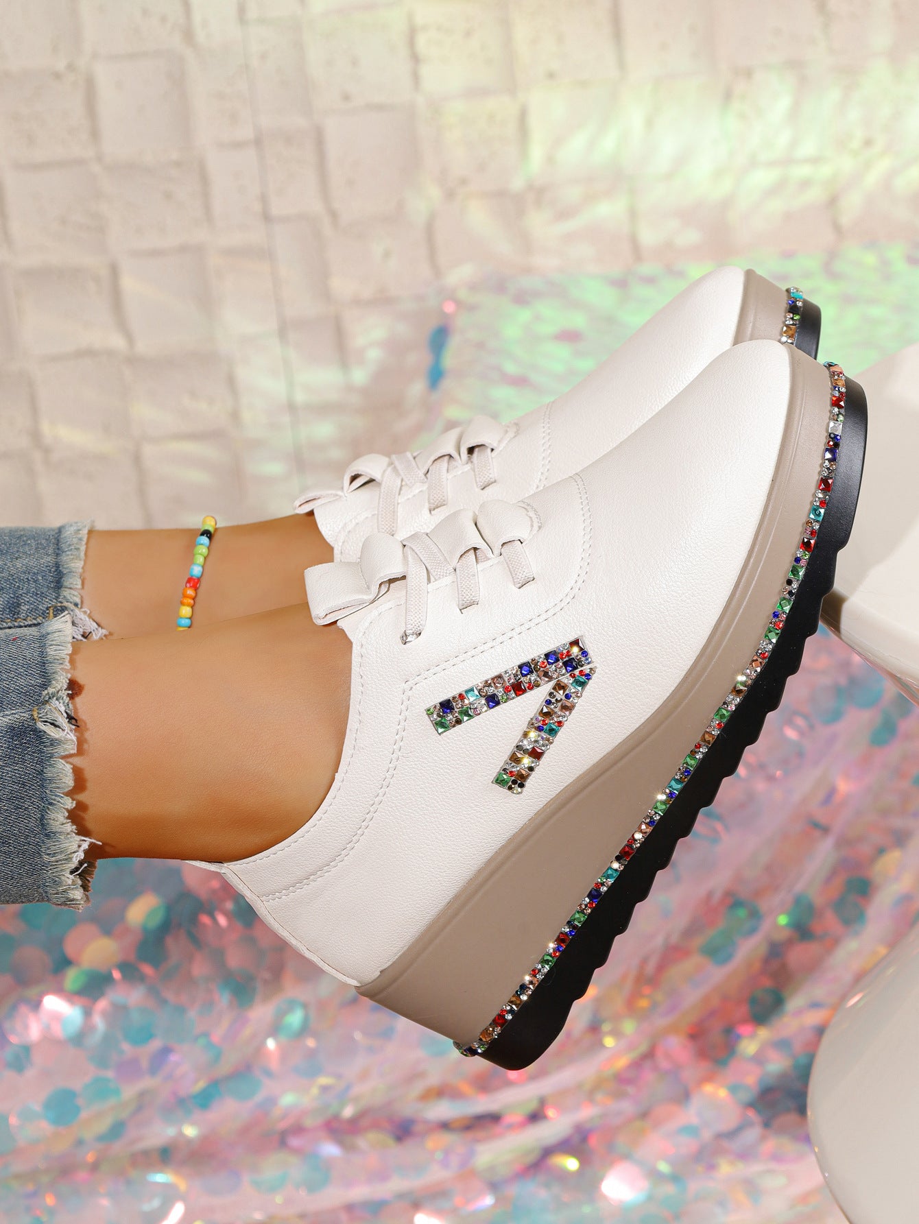 White wedge sneakers with colorful rhinestone embellishments on the side and sole.