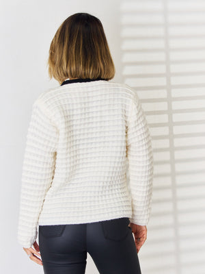 Textured knit white cardigan with contrast black trim and button front detail.