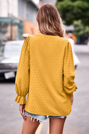 Gold textured dot V-neck blouse with ruffle cuffs and long puff sleeves.