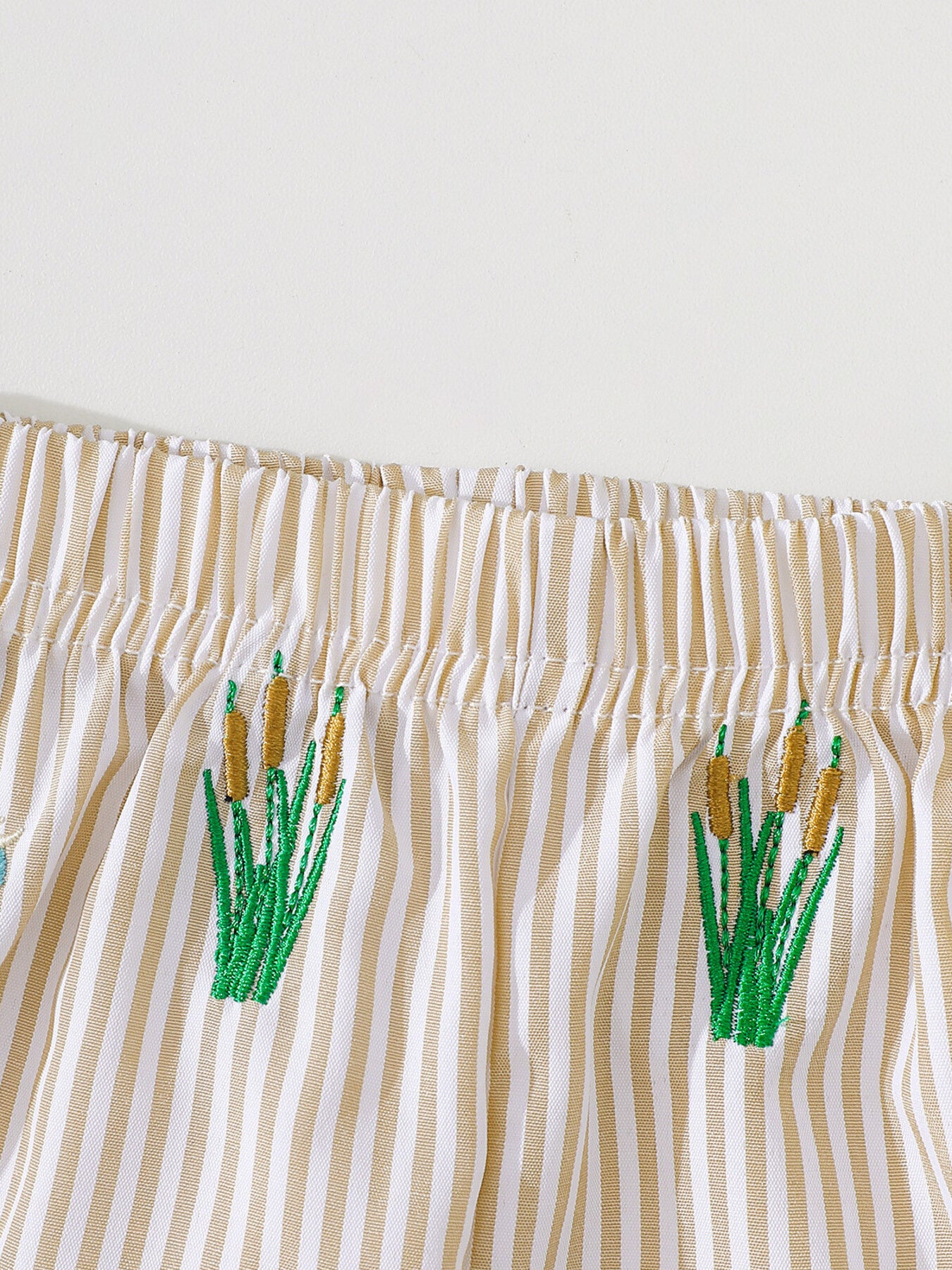 Baby shorts with tan and white stripes and embroidered cattails.