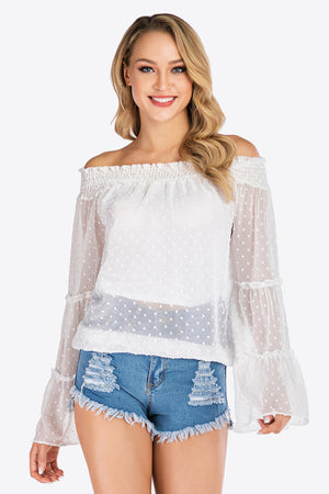 White dotted swiss off-shoulder blouse with ruffle sleeves and smocked neckline.