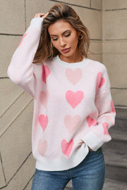Pink knit crewneck pullover sweater with allover heart motif and white cuffs.