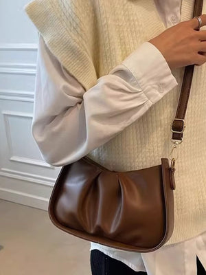 Brown ruched crossbody bag with braided strap detail.