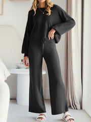 Black acrylic loungewear set with wide-leg pants and a crewneck sweater.