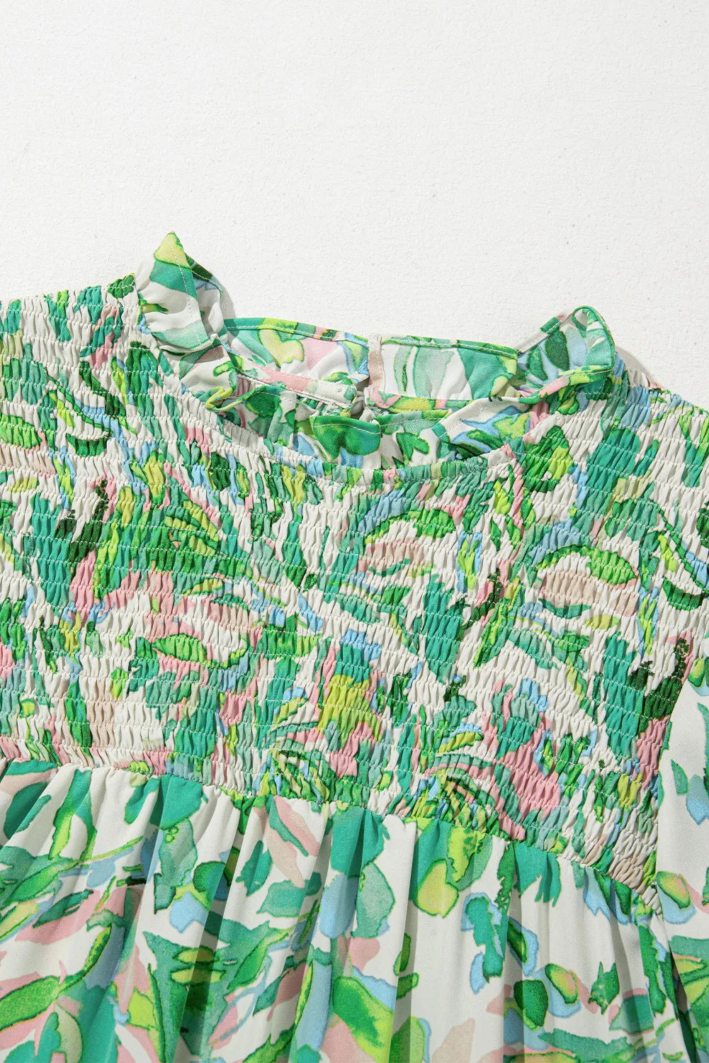 Green floral smocked yoke blouse with ruffled mock neck and voluminous sleeves.