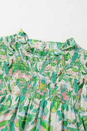 Green floral smocked yoke blouse with ruffled mock neck and voluminous sleeves.