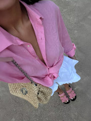 Pink cotton oversized button-up shirt with rolled sleeves and a knotted hem.