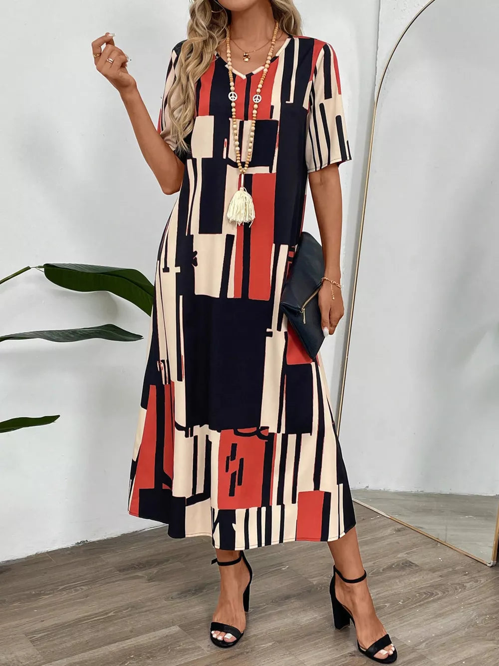 Geometric V-neck midi dress in dark blue, red, and cream with short sleeves.