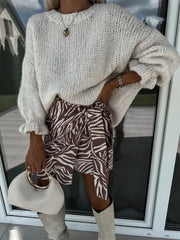 Cream voluminous sleeve knit sweater with ruffled cuffs, paired with a zebra print wrap skirt.