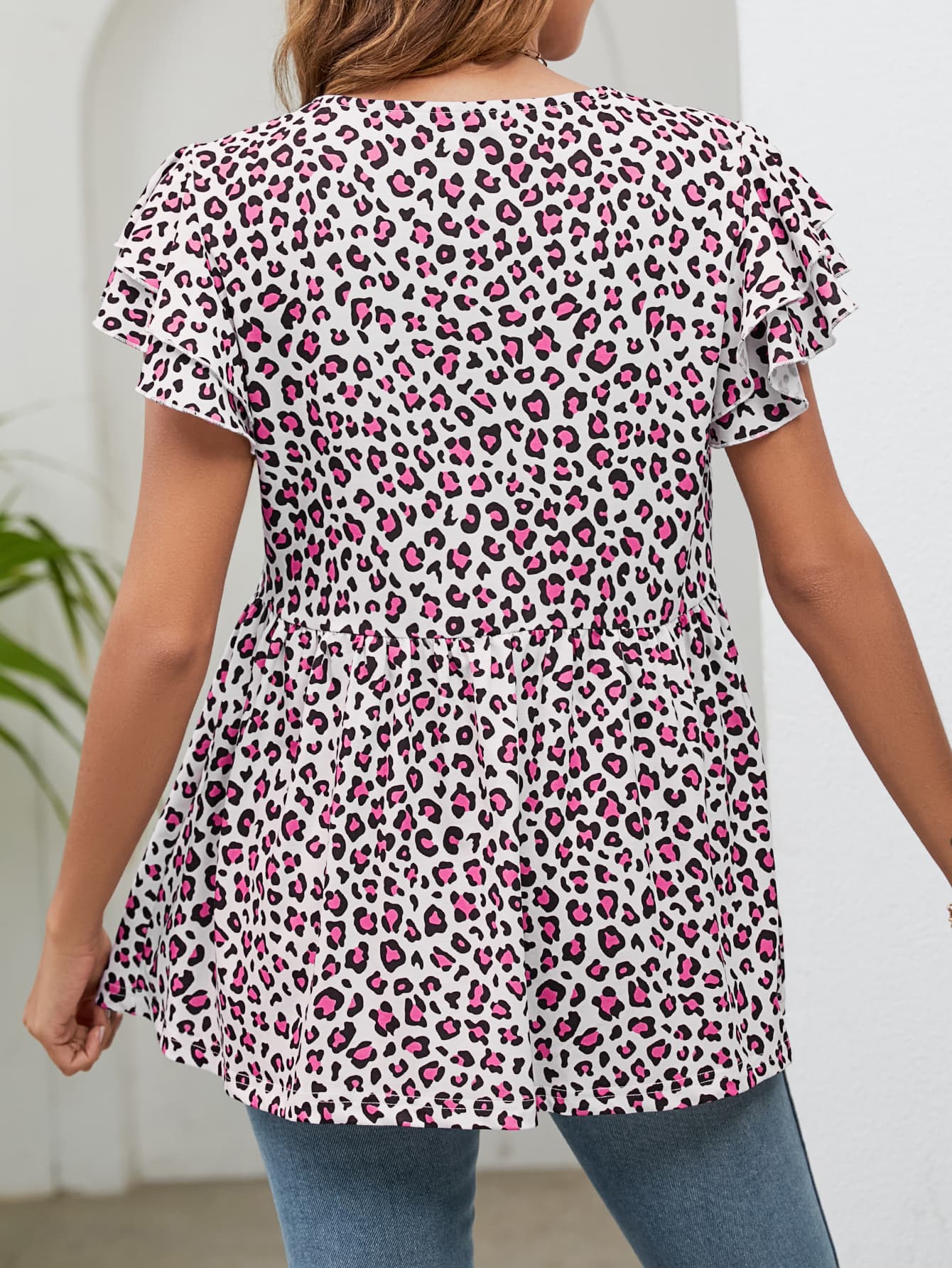 Pink leopard print babydoll blouse with flutter sleeves and cinched waist.