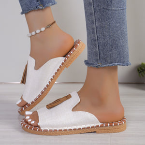 White tassel-embellished open-toe slide sandals with decorative stitching.