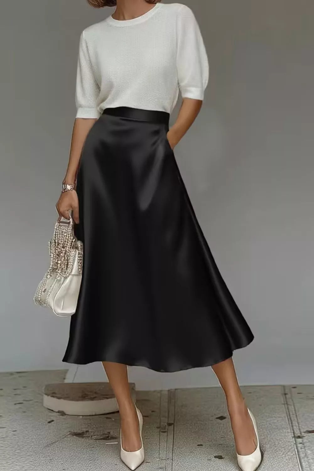 Black a-line midi skirt with hidden pockets, made of lustrous fabric.