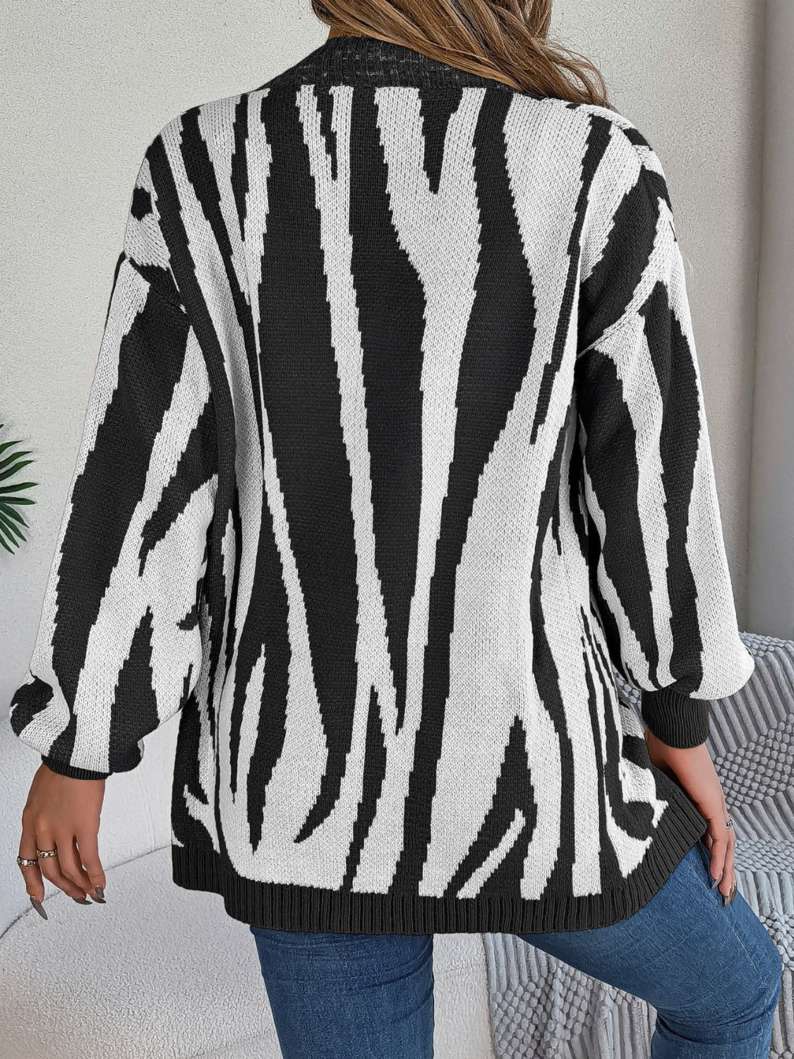 Black and white zebra stripe open-front knit cardigan with long sleeves.