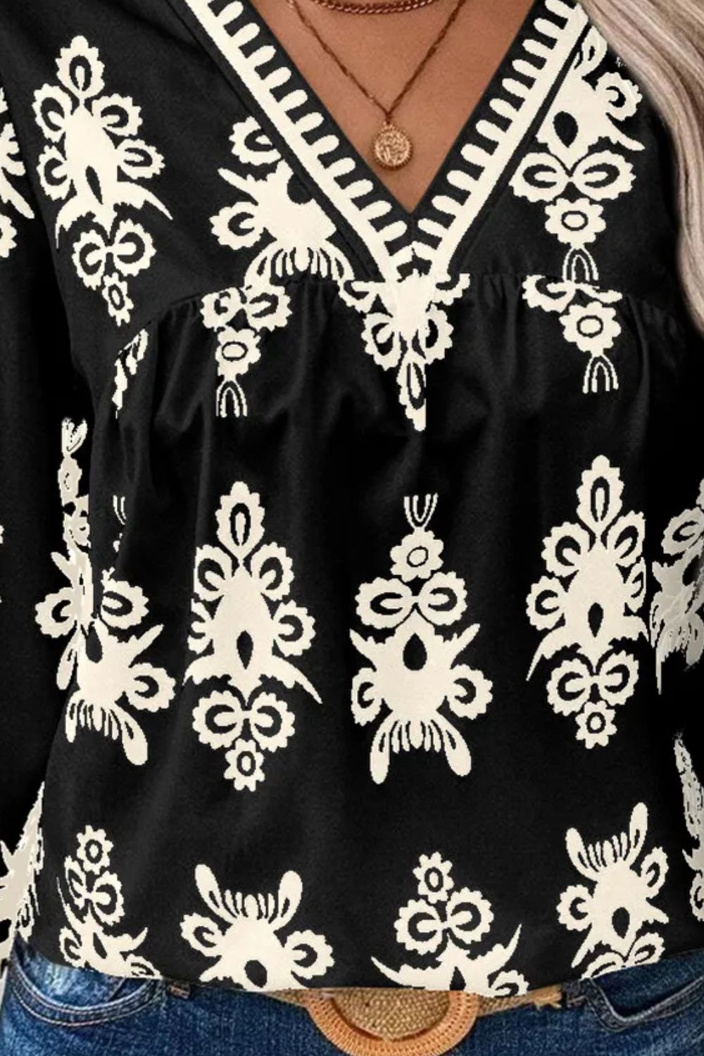 Black V-neck blouse with white embroidered pattern and contrast trim detail
