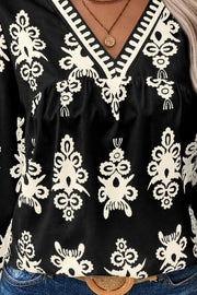 Black V-neck blouse with white embroidered pattern and contrast trim detail