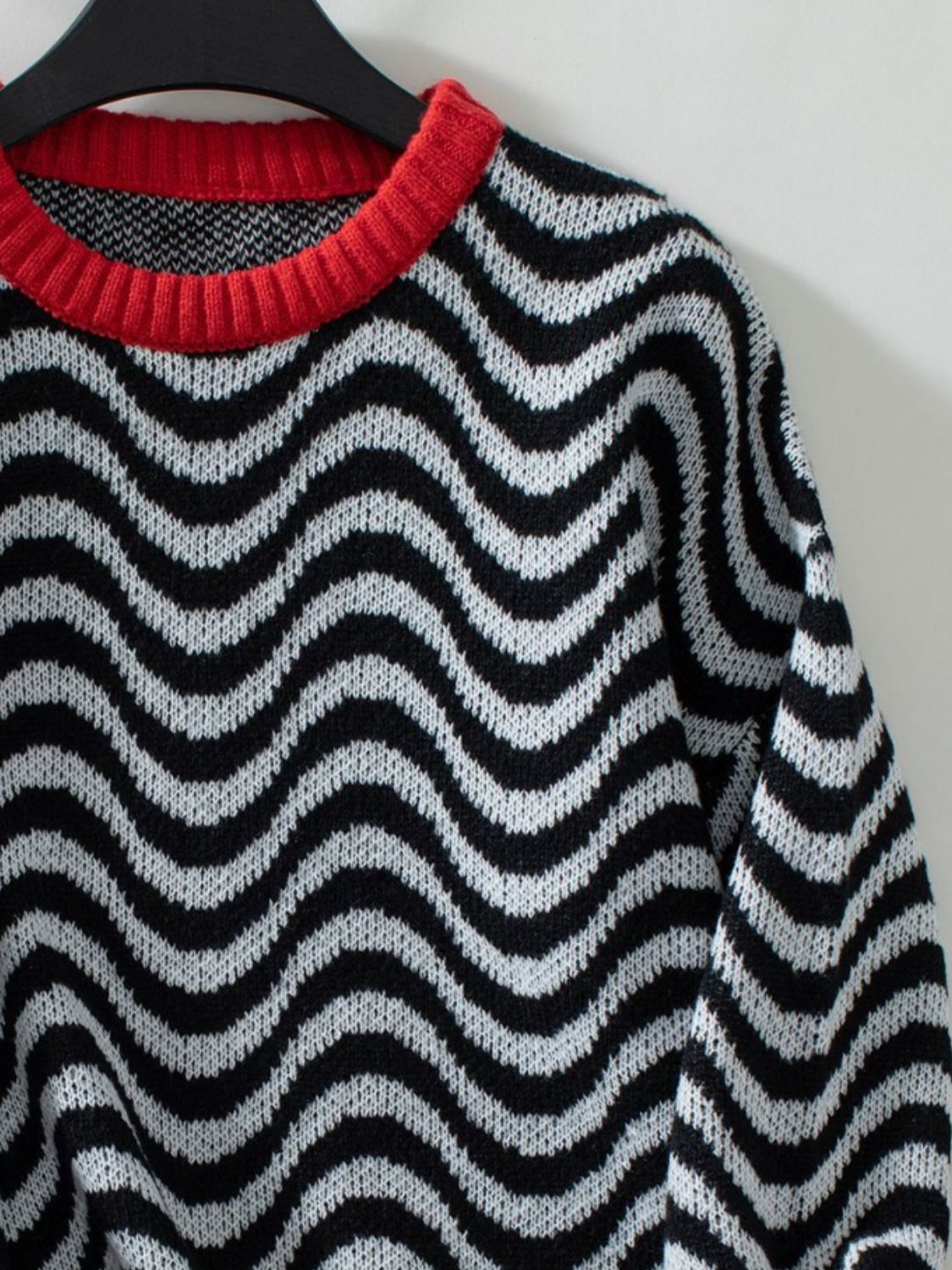 Black and white wavy stripe knit sweater with a red contrast collar.