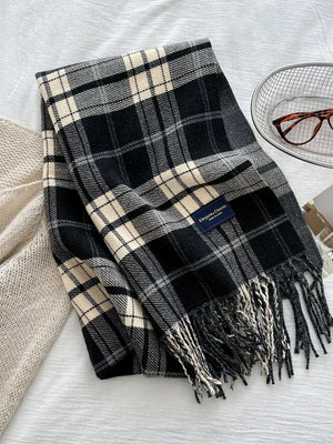 Black plaid scarf with fringe and cream accents, featuring a classic tartan pattern.