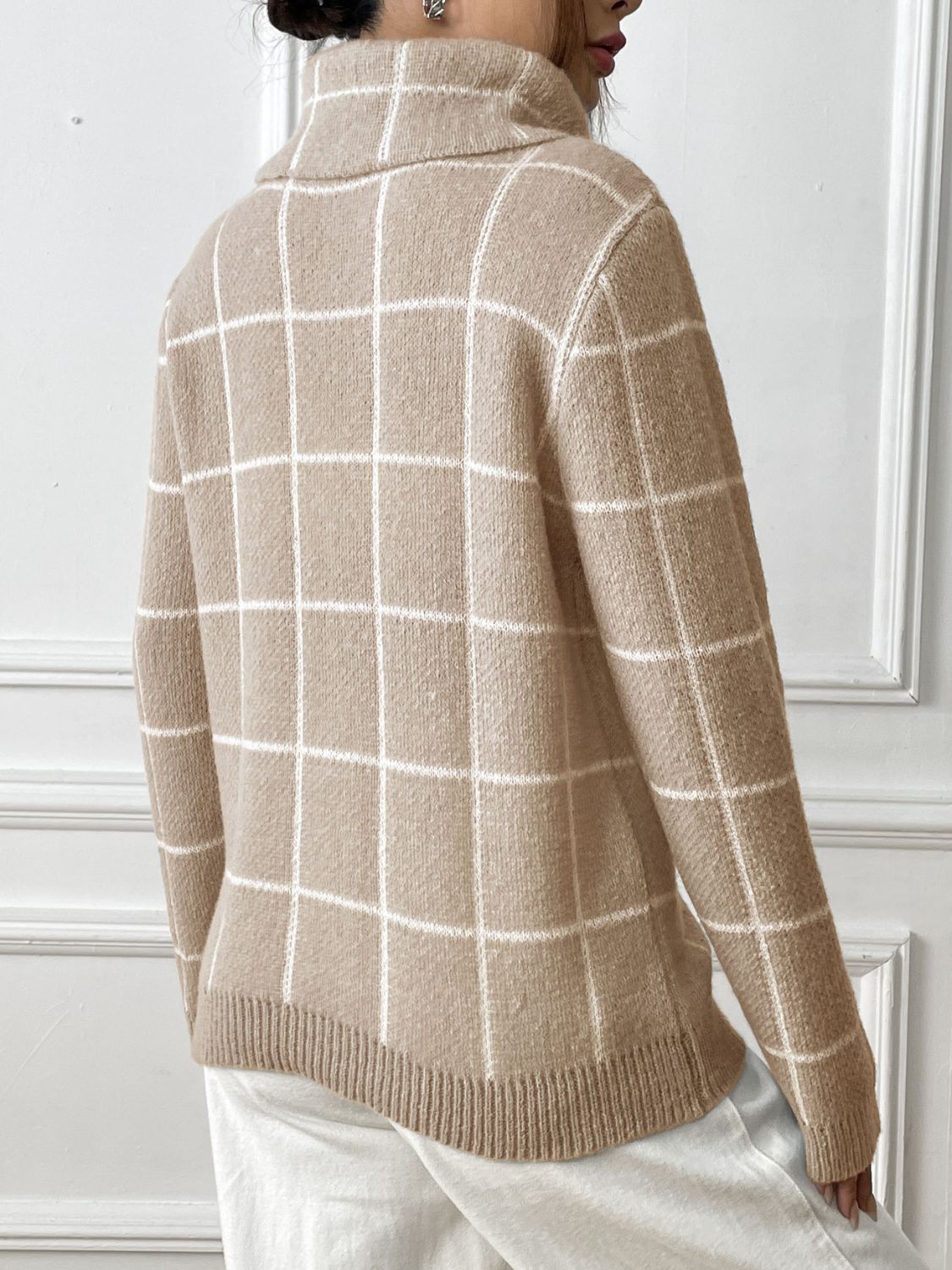 Tan turtleneck sweater with white grid pattern and ribbed trim.