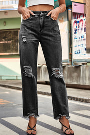 Distressed hem straight leg jeans in dark wash denim with ripped knees and frayed ankles.