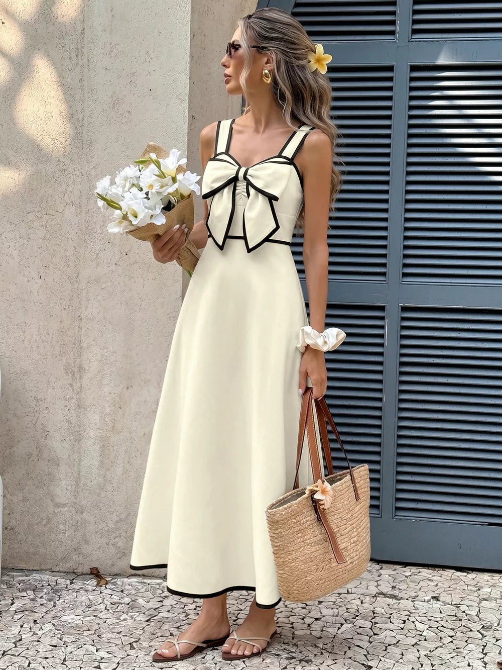 Beige A-line midi dress with black trim and large bow detail on bust.