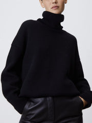 Black relaxed turtleneck sweater with sculptural sleeves and ribbed cuffs.
