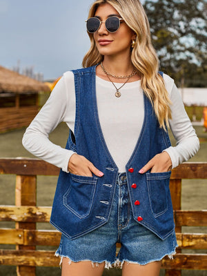 Indigo denim vest with red heart buttons and chest pockets, worn over a white long-sleeve shirt.