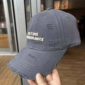 Grey distressed cotton baseball cap with embroidered text and frayed brim.