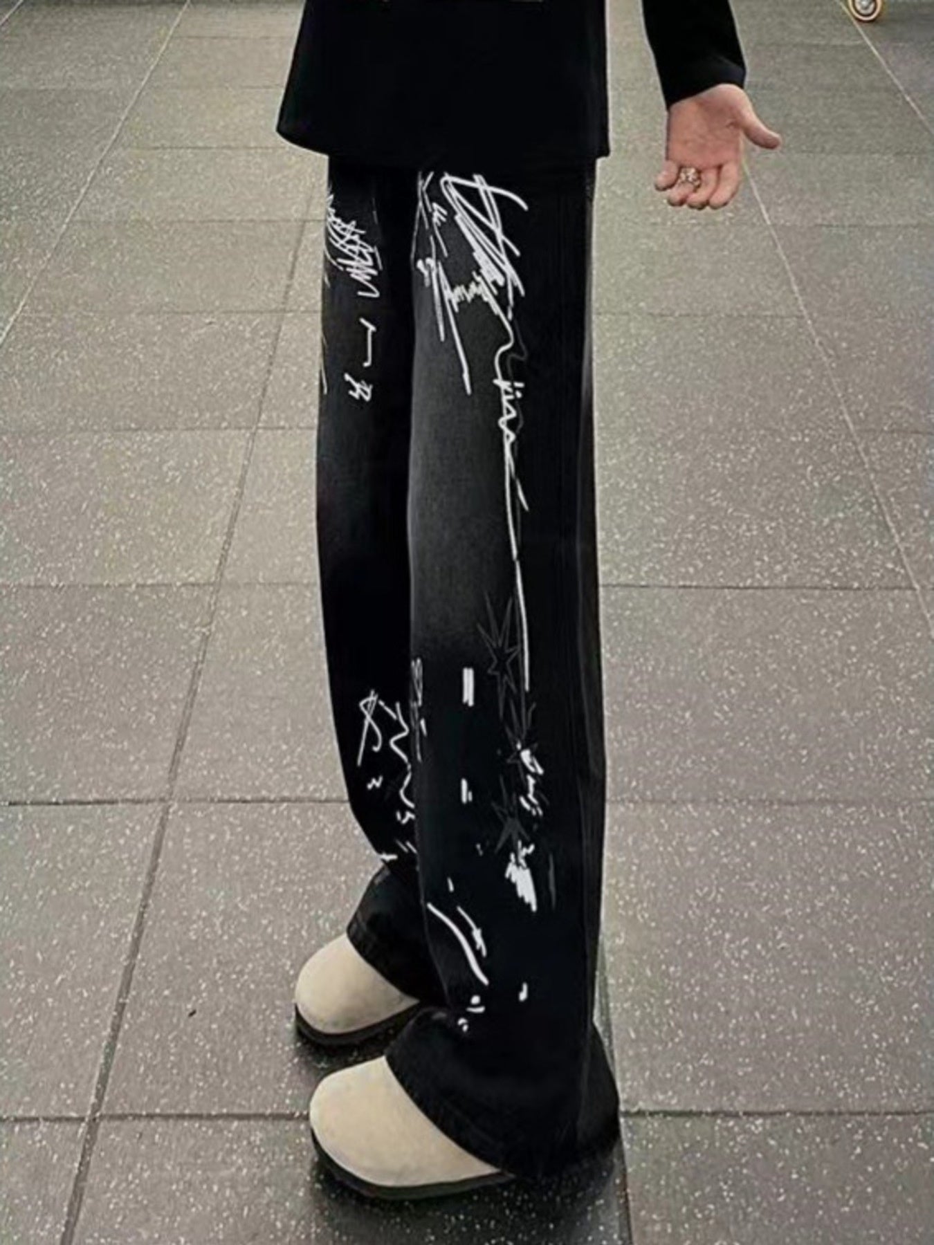 Men's black wide-leg jeans with graffiti print and stars detail.