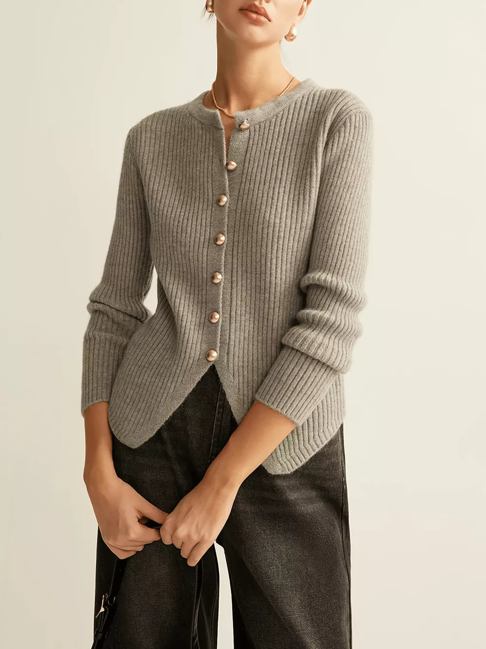Grey ribbed knit cardigan with crew neck, gold buttons, and asymmetrical hem.