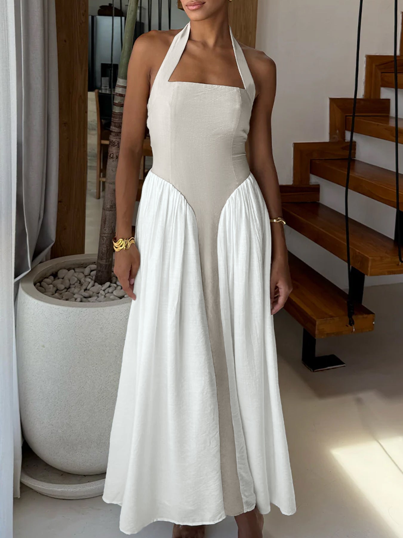 Halter neck maxi dress in beige and white color-block with a flowing skirt.