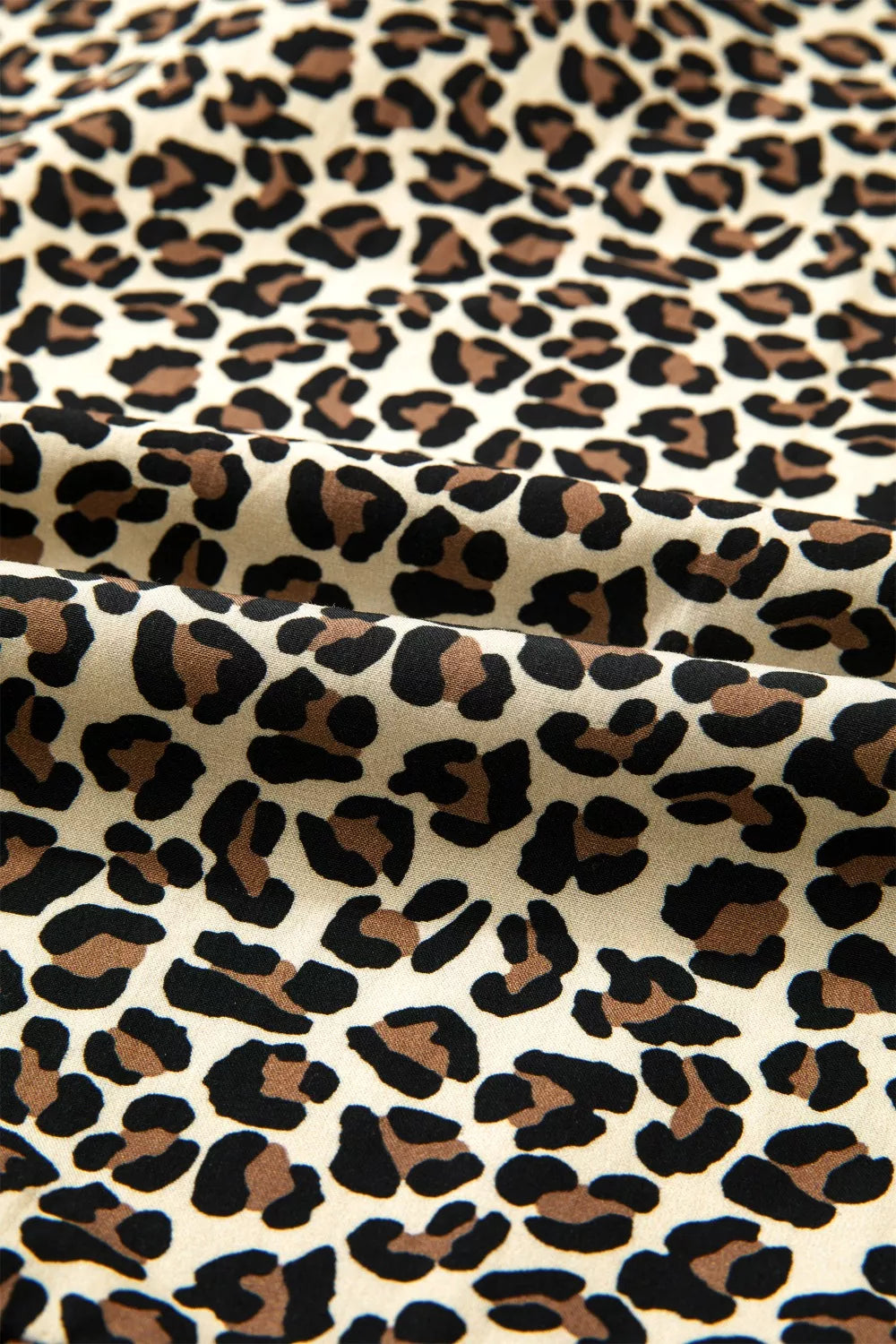 Leopard print mini dress fabric with black and brown spots on a cream background.