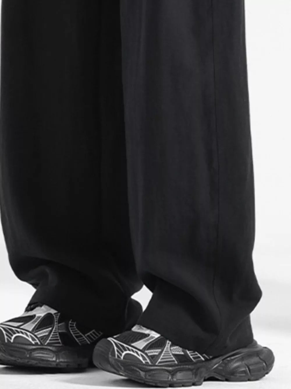 Black loose fit drawstring pants with a relaxed cut, paired with graphic sneakers.