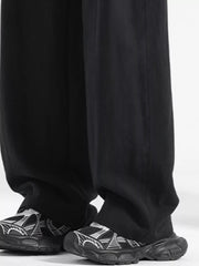 Black loose fit drawstring pants with a relaxed cut, paired with graphic sneakers.