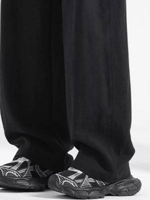 Black loose fit drawstring pants with a relaxed cut, paired with graphic sneakers.