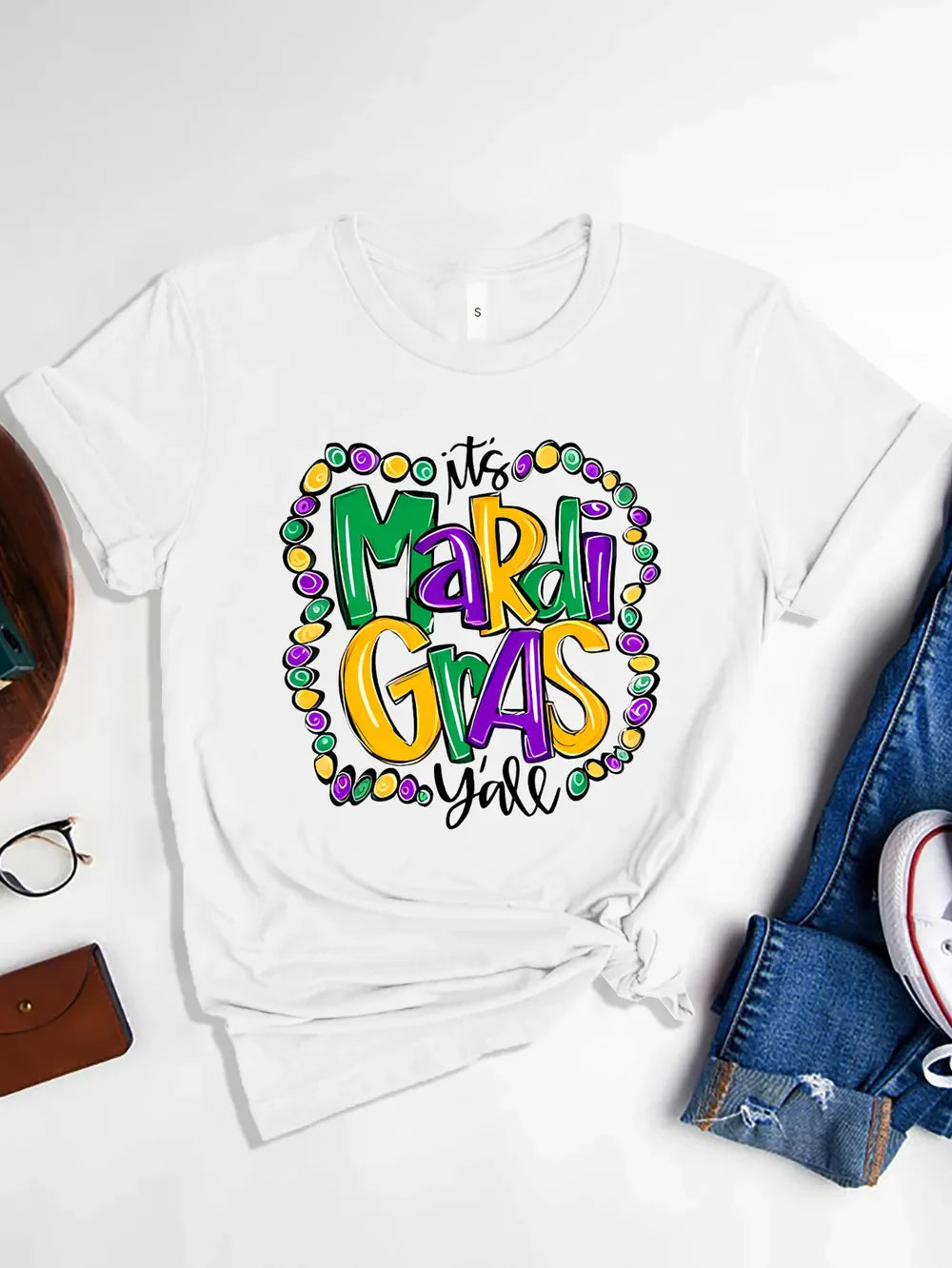 White graphic t-shirt with Mardi Gras beads and text design.