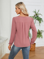 Dusty pink textured pleat-front blouse with ruffle cuffs and long sleeves.