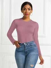 Sculpted ribbed jersey bodysuit in dusty pink with long sleeves and crew neck, styled with jeans.