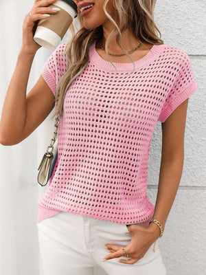 Pink openwork knit crewneck top with short sleeves, styled with white pants.
