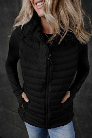 Black quilted puffer vest with fleece collar and zip front, worn over a long-sleeve shirt.