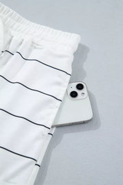 White polyester shorts with black stripes and drawstring waist, showing a pocket detail.