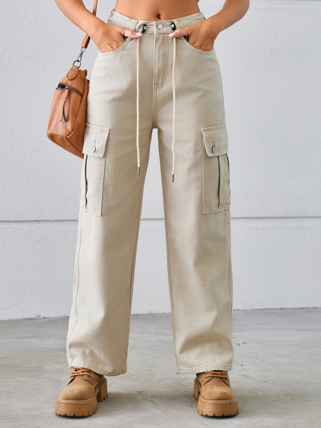 Tan drawstring cargo wide-leg denim trousers with buttoned flap pockets.