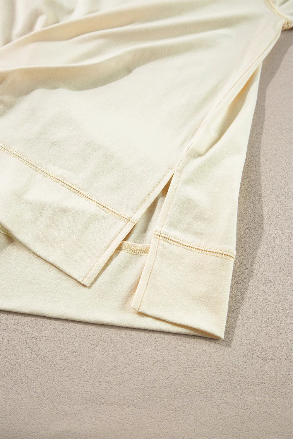 Pastel yellow blouse with side slits and reinforced hem detail.