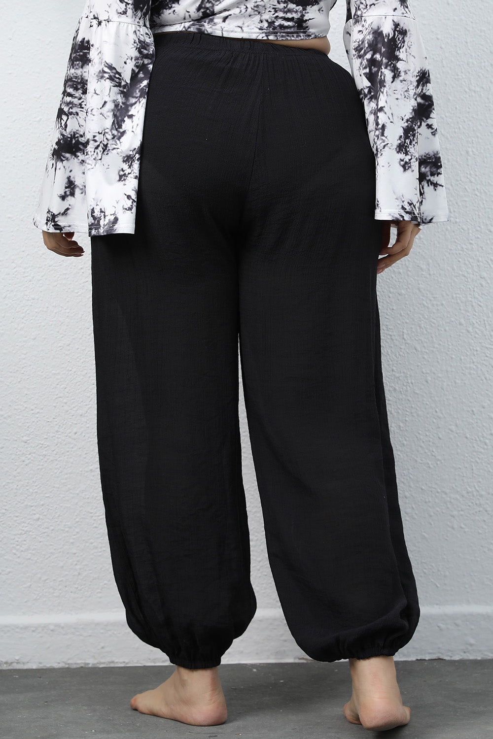 Black textured balloon-leg trousers with drawstring waist and elastic cuffs.