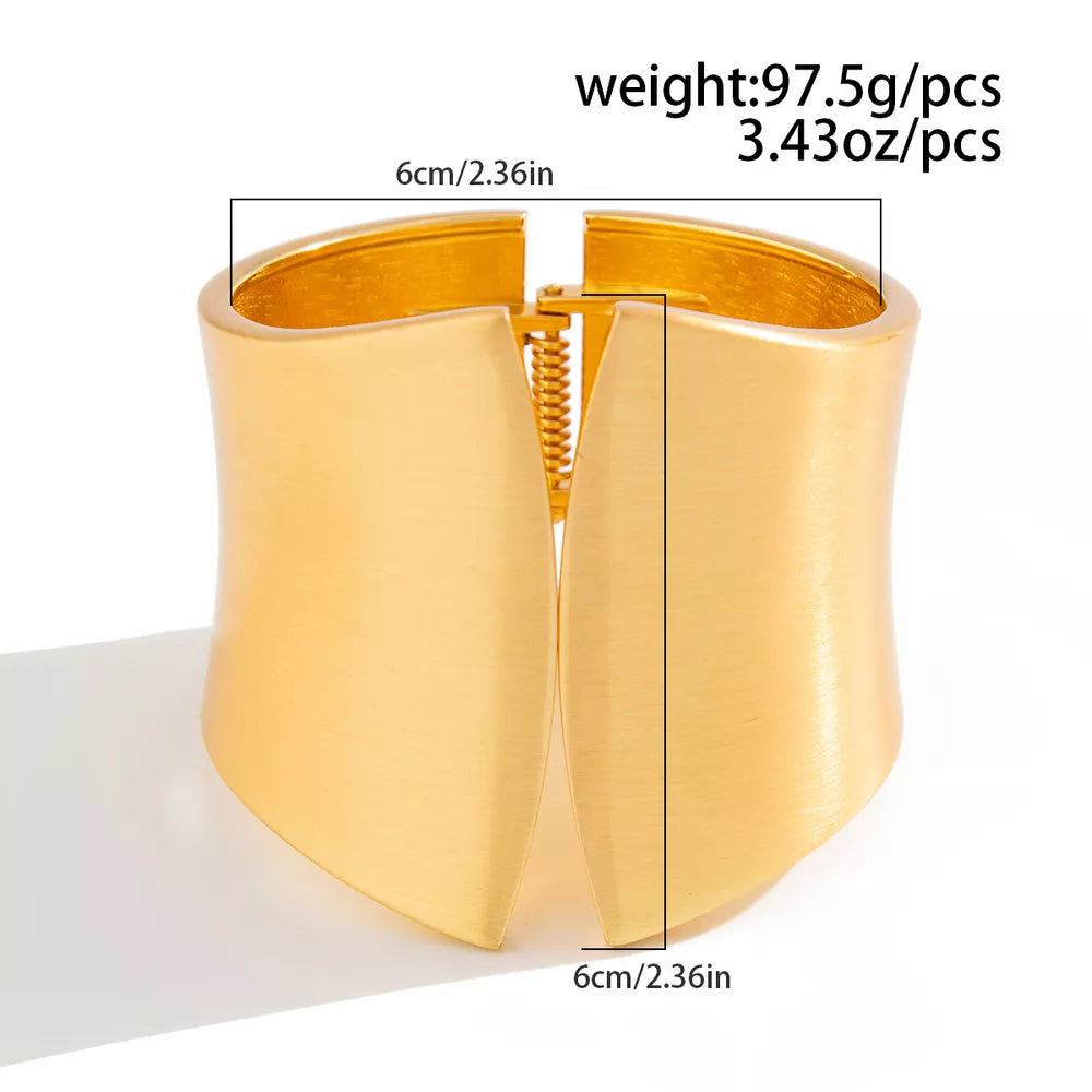 Gold-toned sculptural cuff bracelet with a wide, open design and spring hinge closure.