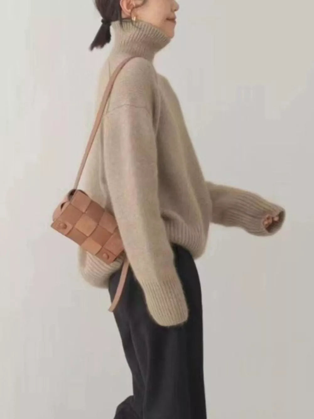 Beige turtleneck knit sweater with dropped shoulders and ribbed cuffs.