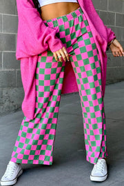 Checkerboard palazzo trousers in fuchsia pink and green, styled with a pink cardigan and white sneakers.