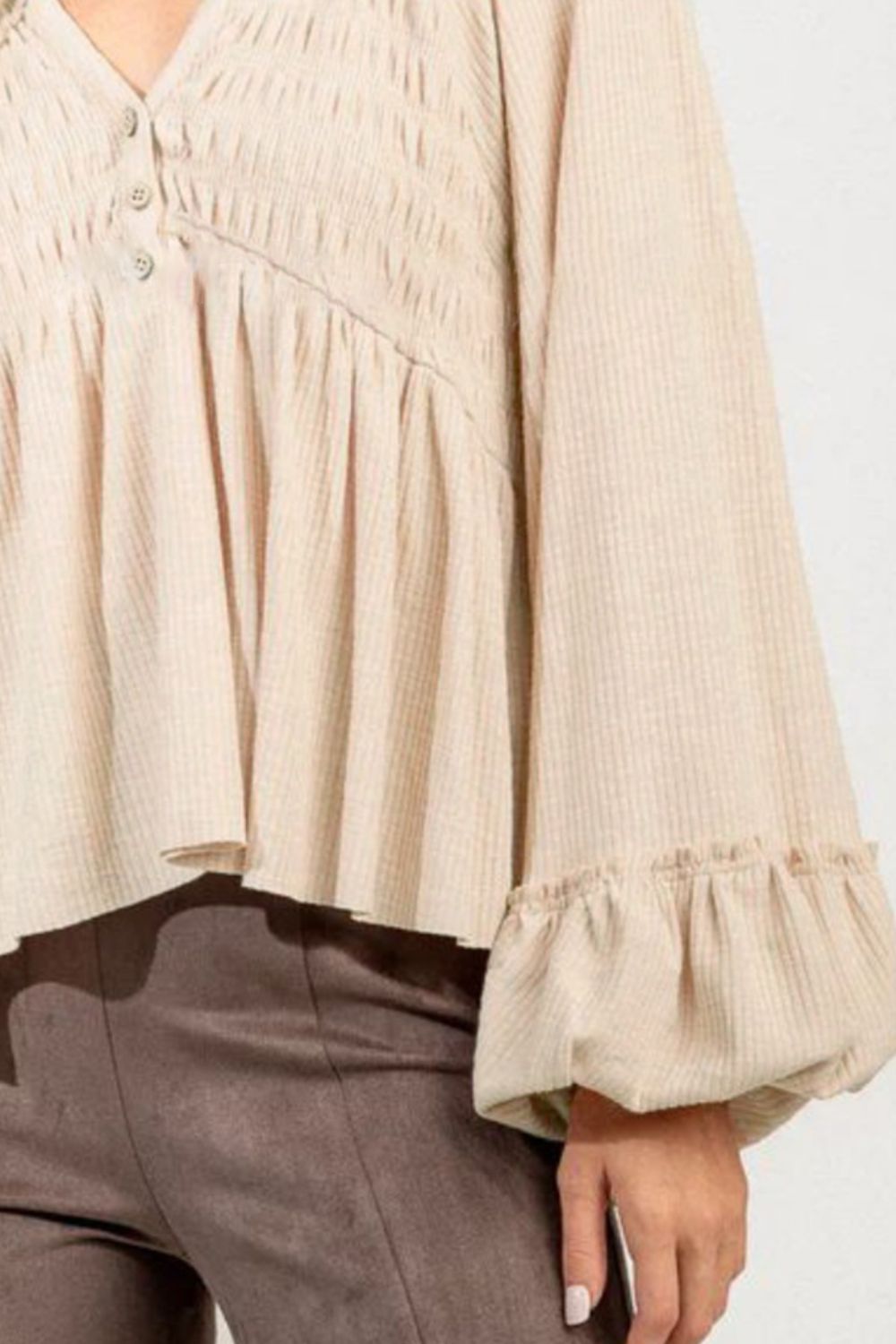 Tan textured ribbed peplum blouse with smocked bodice and ruffled cuffs.