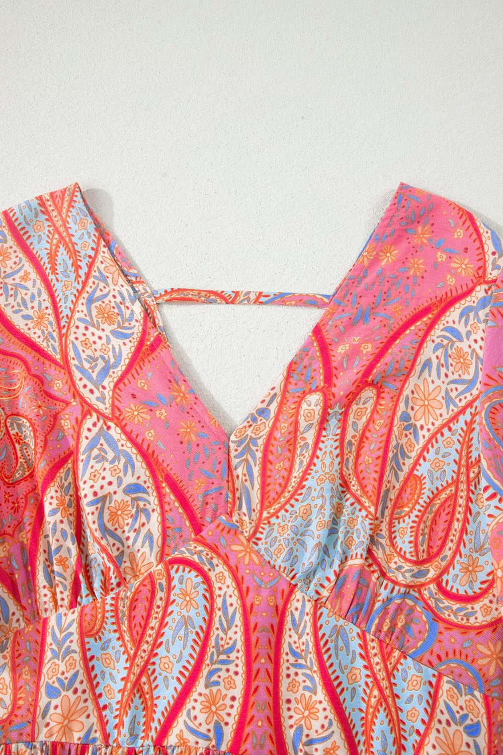 Paisley print v-neck boho dress with criss-cross back detail in burnt coral and pink.