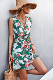 White floral zip-front mini dress with tie waist and green leaves.