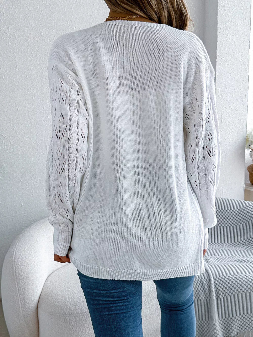 White openwork long sleeve acrylic cardigan with cable knit detail on sleeves.